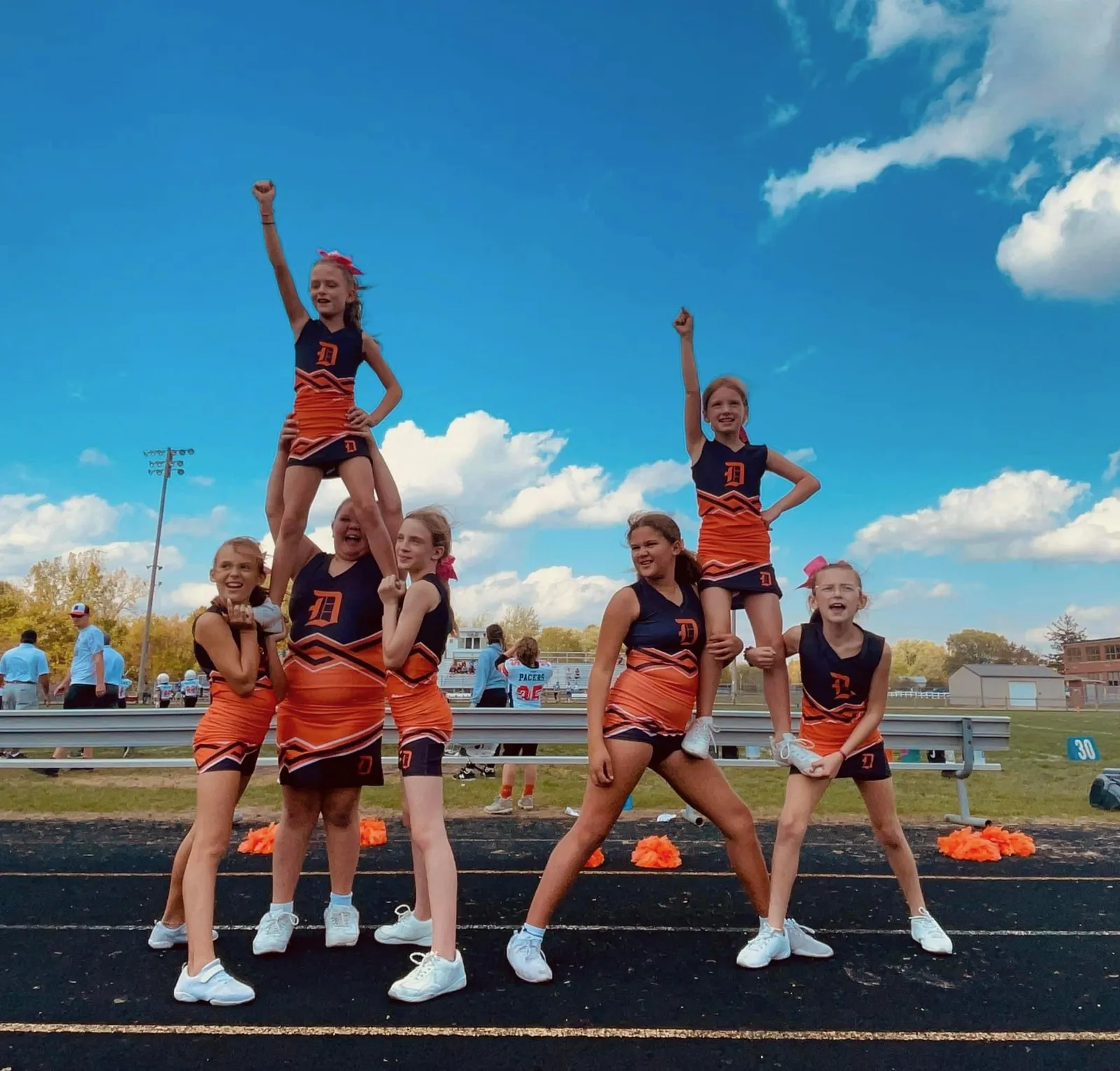 Jr Pacers cheerleaders holding a stunt against the sky